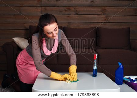 Woman in uniform and rubber gloves cleans table