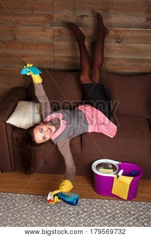 Woman in cleaning uniform poses on a couch