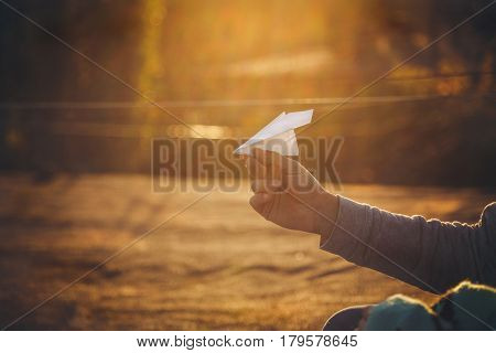 Paper airplane in man's hand at sunset