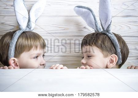 Two cute little brothers wearing bunny ears playing egg hunt on Easter. Adorable children celebrate Easter at home