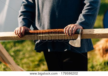 Old axe hit on a firewood chopping block with work gloves.