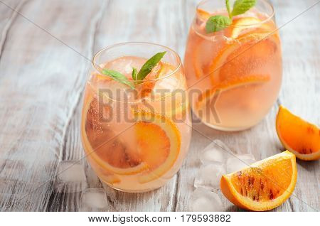 Cold refreshing drink with blood orange slices in a glass on a wooden background. Selective focus, copy space.