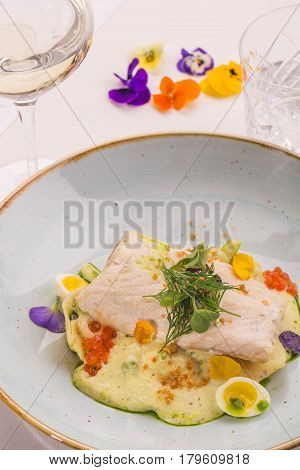 Giving of a sturgeon with pelmeni from a smoked sterlet with a glass of white wine and decorated with flowers