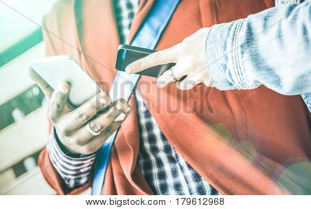 Close up detail of multiracial couple hands having fun with mobile phones - Modern concept of smartphone tech relationships with people flirting together on ciity urban lifestyle - Bright azure filter
