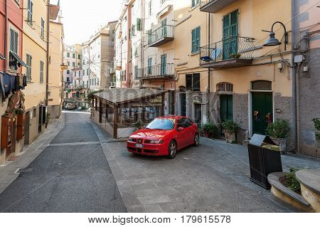 VERNAZZA, ITALY - DECEMBER 2016: Main street of Vernazza town and parked red car in the middle of the street.
