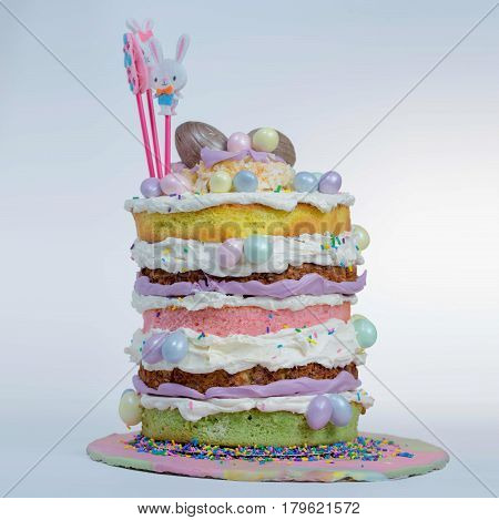 Naked cake with five layers in different flavor and small eggs chocolate attached to it in different color.