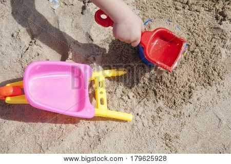 Baby boy playing with sand at the beach. Shovel bucket and wheelbarrow detail
