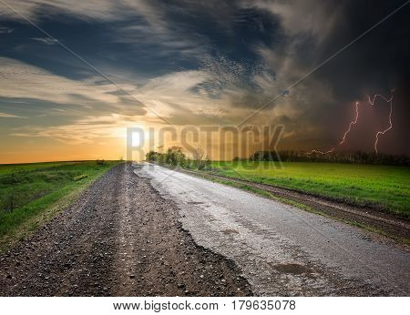 Asphalted road at sunset and stormy sky