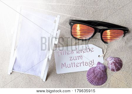 Sunny Summer Label With German Text Alles Liebe Zum Muttertag Means Happy Mothers Day. Flat Lay View. Summer Decoration With Deck Chair, Seashells And Sunglasses. Greeting Crad With Sand Background