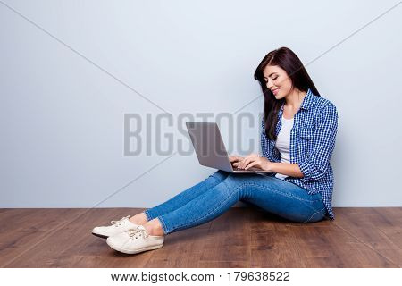 Cute Young Woman In Checkered Shirt Sitting On The Foor And Using Laptop For Chatting