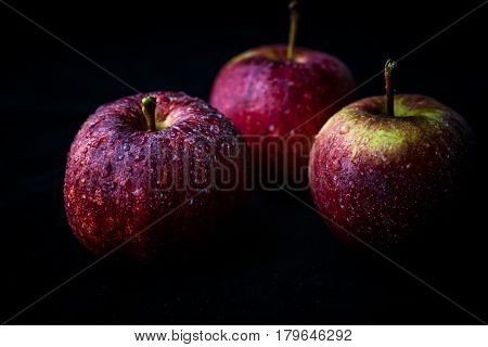 Close up of ripened red apples against black background