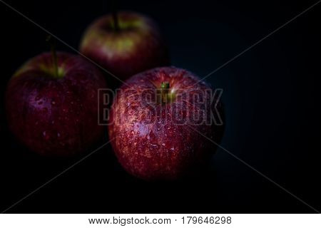 Close up of ripened red apples against black background