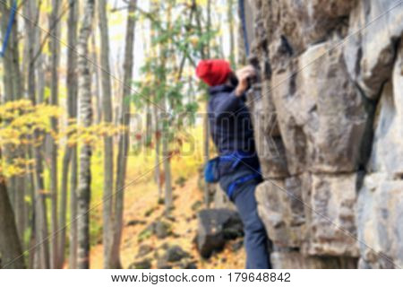 Climber climbs on a rock in blurred for background