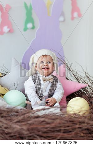 funny baby boy dressed in Easter bunny suit lying in a nest.