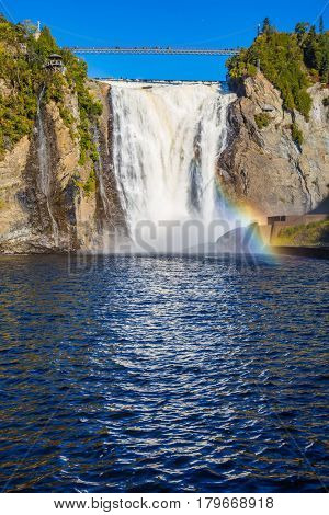 The magnificent rainbow plays in falls splashes. The blue lake and powerful waterfall Montmorency in Montmorency Falls Park, in Quebec. The concept of active and cultural tourism