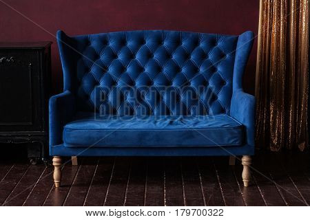 Marsala wall, golden curtain and vintage upholstered blue sofa.