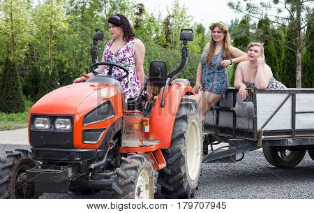 Three beautiful girls plus size on the Minitractor in the garden nursery