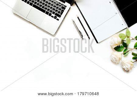 Modern minimalistic work place. White office desk table with laptop keyboard, pen, white roses, vintage tray. Top view with copy space, flat lay