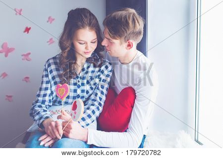 Beautiful couple having a fun together. Posing with lollipops on colorful background.