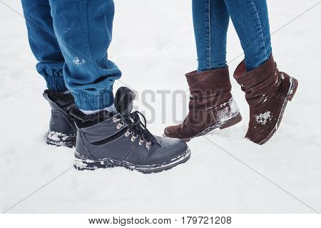 Closeup of male and female legs during a date in winter, shorter woman slid up to reach taller man on love scene, couple kissing
