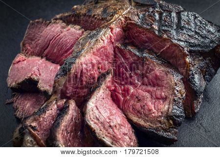 Barbecue dry aged Wagyu Bistecca alla Fiorentina as close-up on a black slate 