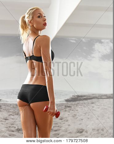 Sexy, athletic, blonde woman in the gym, against the background of the mirror, with dumbbells in hands. Sports, sportswear, health, a beautiful body, full-length portrait, body Parts