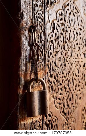 Part of ancient wooden door with carving and vintage looking padlock at Itchan Kala (Xiva Ichon Qala) UNESCO world heritage, Khiva, Uzbekistan.