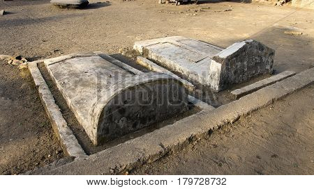 Two grey colored stone graves with tombstones at Bena a traditional village of the Ngada people in Flores near Bajawa Indonesia.
