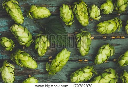 Green hops malt and wheat grain on a wooden old table ingredients to make beer and bread agricultural background blue tone