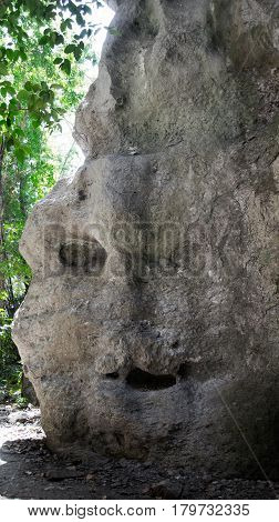 Grey natural rock at daytime that looks like a face with eye mouth and nose in Flores Indonesia.