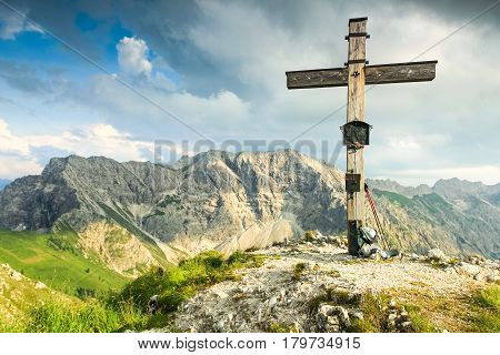 Wooden summit cross and summer colors. Morning or evening light in the mountains. Hiking in the mountains and taking a rest on a peak. Panoramic view.