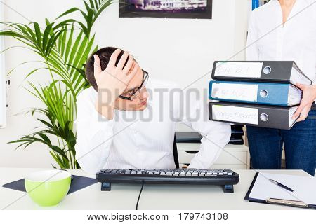 young programmer gets two folders of bug reports and one with change requests. looks like he won't be able to leave the office early today.