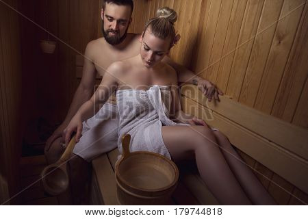 Young couple enjoying the sauna session together and relaxing