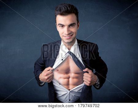 Businessman tearing off his shirt and showing mucular body concept on background