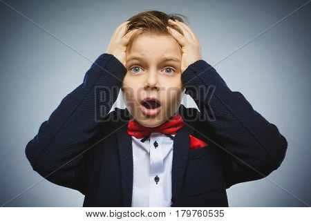 Closeup Portrait of handsome boy with astonished expression while standing against grey background.