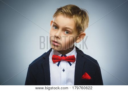 Closeup Portrait of handsome boy with astonished expression while standing against grey background.