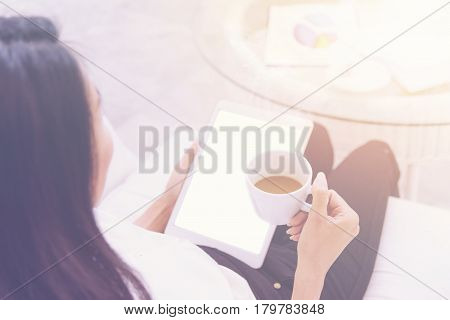Woman drinking tea and using tablet in coffee shop for summary of Business performance report