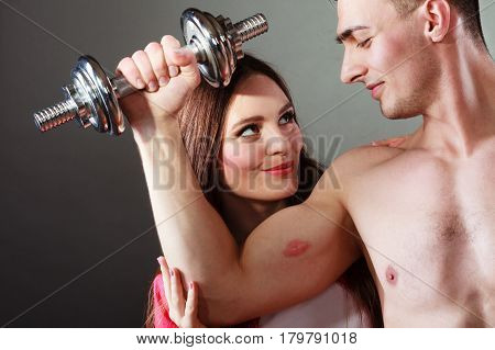 Bodybuilding. Strong man exercising with dumbbells. Closeup muscular guy flexing lifting weights girl looking admiringly kissing his biceps.