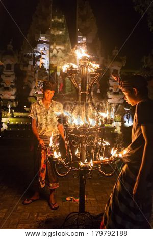 Ubud, Indonesia - August 8, 2016: Unidentified balinese men light candles before a traditional Kecak Fire Dance ceremony in Hindu temple.