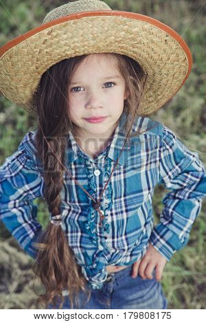 in the field is little beautiful girl Cowboy