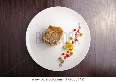 cooked fish fillet of pike-perch on a bed of onion served with a lemon and red currant