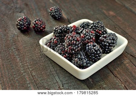 Blackberry fruit on wood background. Forest fruit in white idaeus. Delicious fresh berries.