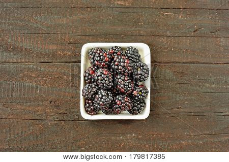 Blackberry fruit on wood background. Forest fruit in white idaeus. Delicious fresh berries.