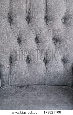 Seamless background texture close up of a grey sofa back with button detail on a thick cloth