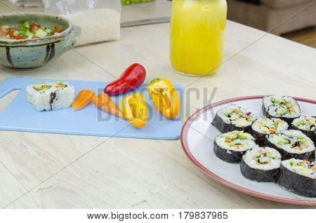 Vegan home made sushi, orange juice and vegetable on a board