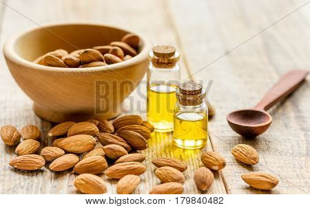 natural cosmetic set with almond oil and bowl of almonds on brown wooden table background