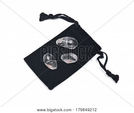 Tumbled clear quartz on black velveteen crystal pouch isolated on white background