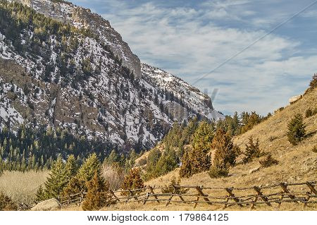 Buck and rail fence with mountains and a blue sky with clouds