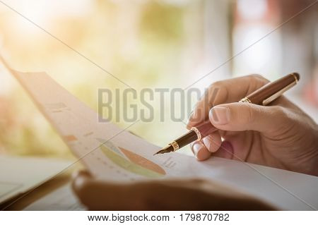 hand hold fountain pen pointing stock maket paper in office. vintage effect.
