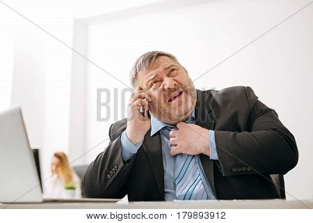 We can handle this. Overwhelmed busy chubby man working at his desk and discussing some important issues on the phone while being under pressure